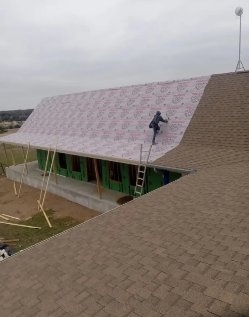 Worker preparing underlayment for a metal roof installation in Crestline
